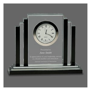 May include: A rectangular glass clock with a silver clock face and black accents. The clock face displays Roman numerals. Text on the clock reads "Presented to Jane Smith" and "American Association of Veterinarians."