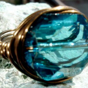 May include: A turquoise blue gemstone ring with a gold wire wrap setting.