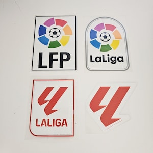 Può includere: Quattro adesivi con loghi associati a La Liga, una lega calcistica professionistica spagnola. Gli adesivi includono il logo La Liga con un pallone da calcio e i testi "LaLiga" e "LFP". I loghi hanno forme e colori diversi.
