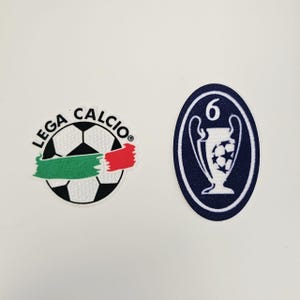 May include: Two embroidered patches. One is a soccer ball with the text "LEGA CALCIO" and a green and red stripe. The other is an oval with a trophy and the number "6".