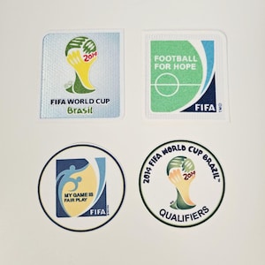 May include: Four patches featuring FIFA World Cup Brazil 2014 logos. One patch has the FIFA World Cup trophy and the text "Brasil". Another says "Football for Hope". The other two patches have the text "My Game is Fair Play" and "Qualifiers".