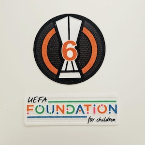 May include: Two embroidered patches. The top patch is circular with a black border, orange accents, and a white and orange design with the number 6. The bottom patch is rectangular with the text "UEFA FOUNDATION for children".