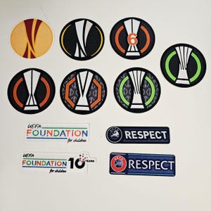 Op de afbeelding: Een verzameling geborduurde patches met het UEFA Europa League-logo in verschillende ontwerpen. Inclusief patches met het woord "Respect" en "UEFA Foundation for children". De patches zijn in verschillende kleuren.