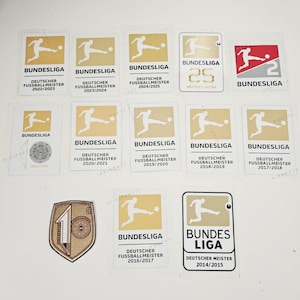 Puede incluir: Colección de pegatinas de la Bundesliga con el logotipo y texto de la liga, con años de 2014/2015 a 2024/2025. Las pegatinas son doradas y blancas, con un jugador de fútbol pateando un balón.