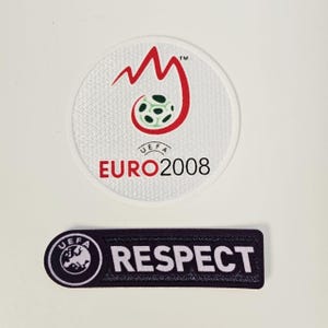 Puede incluir: Dos parches: uno circular con el logo de la UEFA EURO 2008, con un diseño rojo y un balón de fútbol. El segundo es un parche rectangular con la palabra "RESPECT" en letras blancas.