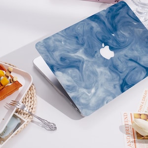 Könnte beinhalten: Eine blaue und weiße Marmor-Laptop-Haut mit einem weißen Apple-Logo. Die Haut ist für ein MacBook konzipiert.