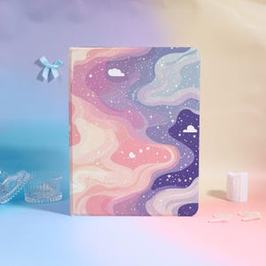 May include: A notebook with a colorful, abstract design featuring swirling patterns in shades of pink, purple, and blue, with white stars and cloud accents. The notebook has a soft cover and is likely for journaling or note-taking.