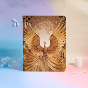 Op de afbeelding: Een gouden phoenix illustratie met uitgestrekte vleugels, tegen een gedetailleerde cirkelvormige achtergrond. Het kunstwerk heeft ingewikkelde veerd details en een warm kleurenpalet, waardoor een majestueus en sierlijk ontwerp ontstaat. De afbeelding staat op een rechthoekig oppervlak.