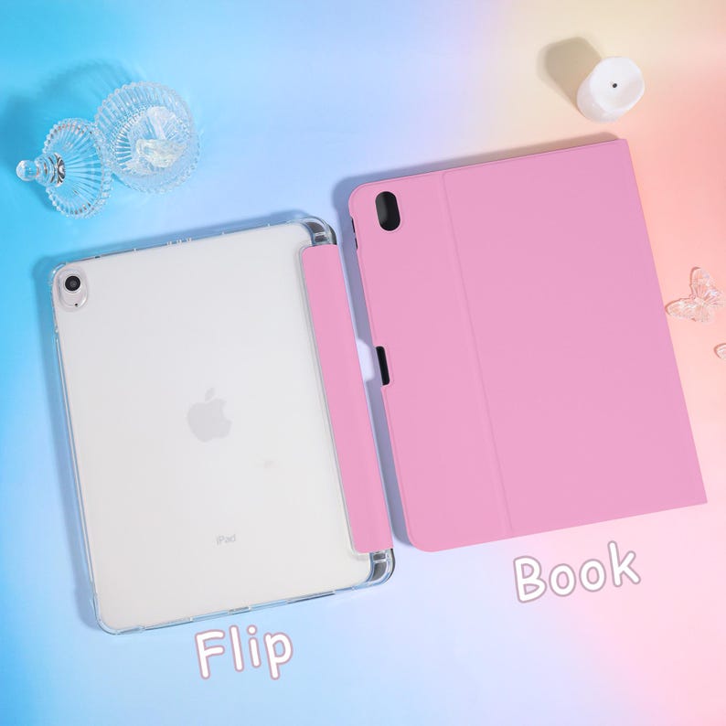 Pode incluir: Uma capa de tablet rosa com um suporte para caneta correspondente e um tablet branco. A capa est&aacute; aberta, revelando a tela do tablet. A palavra "Flip" est&aacute; escrita na parte inferior esquerda e "Book" na inferior direita.