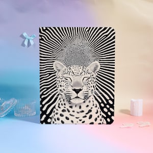 Può includere: Un taccuino in bianco e nero con un leopardo con gli occhi chiusi. Il leopardo è centrato su uno sfondo di linee nere e bianche radianti. Il leopardo ha macchie nere ed è in uno stato zen.