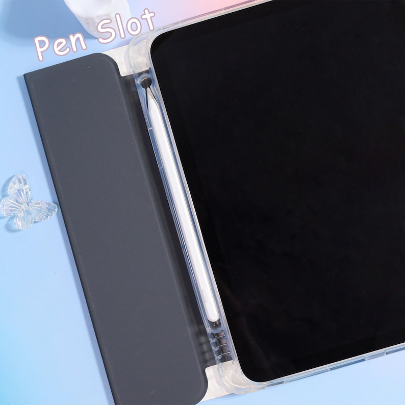 Pode incluir: Uma capa transparente para tablet com tela preta e caneta branca. A capa tem uma capa cinza escuro com as palavras "Pen Slot" impressas na parte superior. Uma decora&ccedil;&atilde;o de borboleta transparente &eacute; vis&iacute;vel no lado esquerdo.
