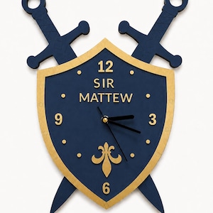 Könnte beinhalten: Eine Wanduhr in Schildform mit zwei gekreuzten Schwertern dahinter. Der Schild ist dunkelblau mit goldenem Rand und zeigt den Text SIR MATTEW, die Zahlen 3, 6, 9 und 12 sowie ein goldenes Lilien-Emblem. Schwarze Uhrzeiger befinden sich in der Mitte.