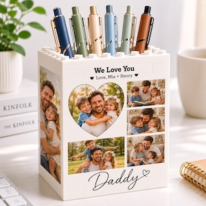 Könnte beinhalten: Ein weißer personalisierter Stifthalter mit Fotos und dem Text "We Love You" und "Daddy". Er enthält sechs Stifte in verschiedenen Farben. Der Stifthalter ist mit Familienfotos verziert.