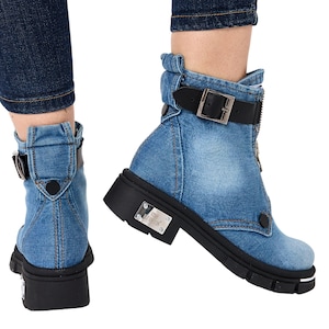 May include: Light blue denim ankle boots featuring a front zipper closure, a black adjustable strap with a silver buckle, and a thick black lug sole. A rectangular silver metal plate with the text "STAR FASHION" is attached to the outer heel.