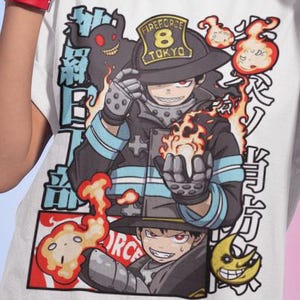 May include: White t-shirt with a graphic of a firefighter holding flames, with Japanese text. The firefighter wears a helmet that says "Fireforce 8 Tokyo". The design includes cartoon flames and a smiling moon.