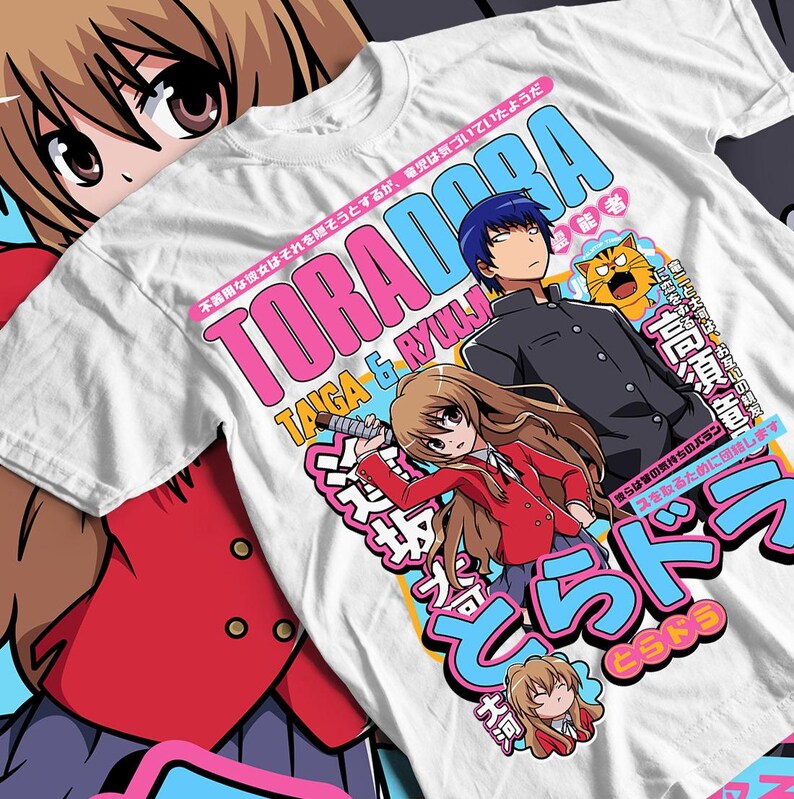 May include: White t-shirt featuring anime characters and Japanese text. The design includes the words "ToraDora" in pink and blue, along with illustrations of two characters and a tiger.