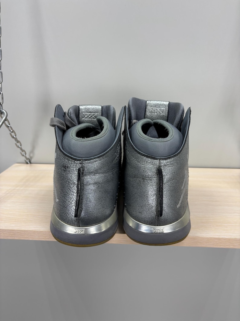 May include: A white ceramic mug with a black handle and the text "But First, Coffee" in a bold, black font. The mug is set against a blurred background, suggesting a cozy setting.