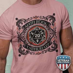 May include: Pale pink t-shirt with a black and red graphic. The design includes a D20 die and the words "MATH ROCK ENTHUSIAST", surrounded by scrollwork. A "Veteran Owned & Operated" badge is visible.