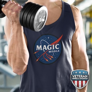 Puede incluir: Camiseta sin mangas azul marino con un diseño gráfico circular con las palabras "MAGIC MISSILE" en blanco, con un diseño rojo y naranja. La camiseta sin mangas la lleva una persona que levanta una mancuerna. Se ve una insignia de "Veteran Owned & Operated".