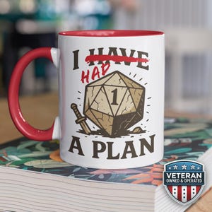 May include: White ceramic mug with a red interior and handle. The mug features the text "I HAVE A PLAN" with a graphic of a die and a sword. A Veteran Owned & Operated badge is visible on the bottom right.
