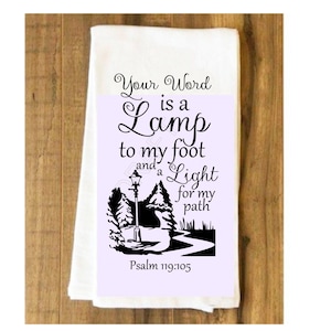 May include: A white kitchen towel with a black and white design featuring a lamppost, trees, and a winding path. The text "Your Word is a Lamp to my foot and a Light for my path" is printed on the towel, along with the verse "Psalm 119:105".