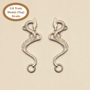 May include: Two silver-colored seahorse-shaped ornaments. Each ornament has a detailed, textured design and a ring at the bottom. The ornaments are for a 1:9 Trad. Model (Toy) Scale.