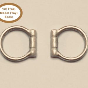 May include: Two silver metal rings with a rounded bar on each side. The rings are 1:9 traditional model (toy) scale.