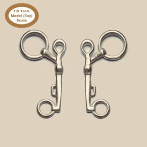 Puede incluir: Un par de bocados de caballo plateados con un anillo en cada extremo. Los bocados están diseñados para ser utilizados con una cabezada de caballo.