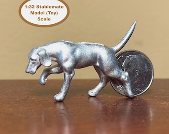 Peut inclure: Un modèle argenté d'un chien en position de marche, avec une pièce de monnaie pour l'échelle. Le modèle est étiqueté "1:32 Stablemate Model (Toy) Scale". La figurine de chien est sur une surface brune.