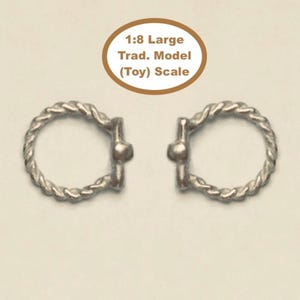 May include: Two silver-colored circular rings with a twisted rope texture and a small central bar detail. Above the rings, an oval graphic contains the text 1:8 Large Trad. Model (Toy) Scale. The items are presented against a plain light background.