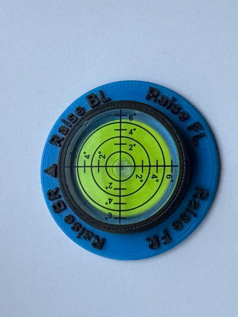 A circular level with a black rim and a blue outer ring. The level has a green bubble level with black markings. The text 'Raise BL' and 'Raise FL' are printed on the outer ring.
