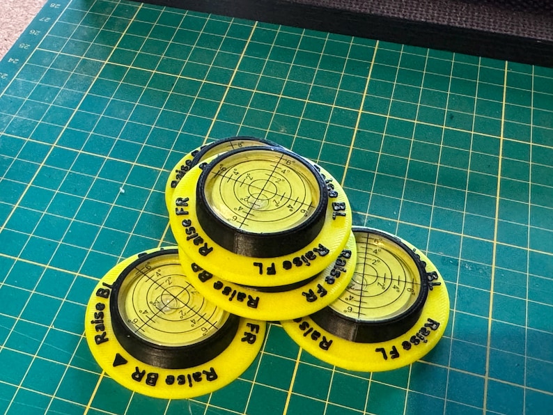 May include: Three circular yellow and black spirit level tools with clear liquid-filled centres featuring crosshair markings. Each unit has black text printed on the yellow rim that reads Raise FR, Raise FL, Raise BR, and Raise BL in various orientations.