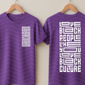 May include: Purple t-shirts with the text "LOVE BLACK PEOPLE LIKE YOU LOVE BLACK CULTURE" in white block letters. The phrase "Black Lives Matter" is also included. The shirts are displayed on wooden hangers.
