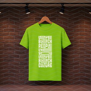 May include: A lime green t-shirt with the text "LOVE BLACK PEOPLE LIKE YOU LOVE BLACK CULTURE" in white block letters. The shirt is hanging on a wooden hanger against a brick wall.