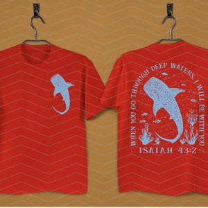 May include: Red t-shirts with a light blue whale shark design. One shirt has the shark on the front, the other has the shark and text: "WHEN YOU GO THROUGH DEEP WATERS, I WILL BE WITH YOU, ISAIAH 43:2."