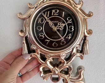 Vintage Manix quartz wall clock. Decorative gold-toned frame and tassels. Hard plastic Resin. Did not test. Light weight.