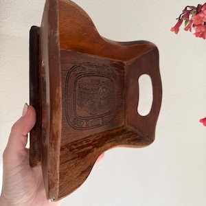May include: A wooden tray with a carved design and a handle. The tray is brown and has a rectangular shape.