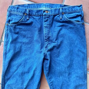 Puede incluir: Unos vaqueros de mezclilla azul de lavado medio con un dise&ntilde;o cl&aacute;sico de cinco bolsillos, cierre de botones y remaches met&aacute;licos de color cobre en las esquinas de los bolsillos. Los vaqueros tienen una cintura est&aacute;ndar con trabillas.