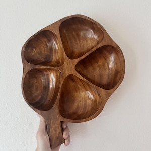 May include: A wooden serving tray with five rounded compartments and a handle. The tray is made of a rich, dark brown wood with visible grain patterns. The compartments are smooth and polished.