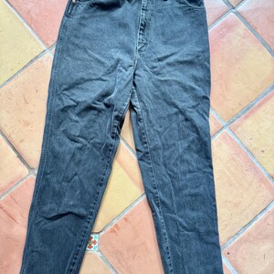 Op de afbeelding: Een donkergrijze spijkerbroek. De jeans heeft een klassiek ontwerp met vijf zakken, een knoop- en ritssluiting en een rechte pijp. De denim lijkt voorgewassen te zijn, met subtiele vervagingen en slijtplekken.