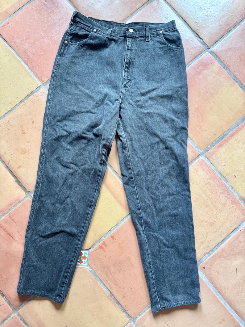 Op de afbeelding: Een donkergrijze spijkerbroek. De jeans heeft een klassiek ontwerp met vijf zakken, een knoop- en ritssluiting en een rechte pijp. De denim lijkt voorgewassen te zijn, met subtiele vervagingen en slijtplekken.