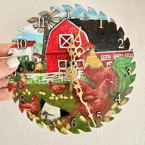 May include: A decorative clock with a farm scene. The clock face is shaped like a saw blade and features a red barn, rooster, hens, and chicks. The clock hands are gold-colored.