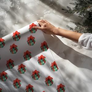 May include: White wrapping paper featuring a repeating pattern of green gift boxes tied with red bows. The paper is being unrolled, revealing the design. The background is a textured, light gray wall with shadows and a sprig of evergreen.