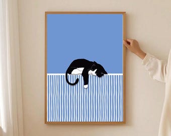 May include: A framed art print featuring a black and white cat resting on a blue and white striped surface against a solid blue background. The artwork has a minimalist style and is set in a wooden frame.