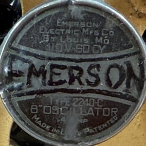 May include: A close-up of a circular metal plate with the embossed text "EMERSON ELECTRIC MFG CO ST LOUIS MO 110V-60 CY". The plate also reads "TYPE 2240-C 8" OSCILLATOR MADE IN L... PATENTED".