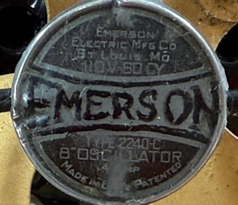 May include: A close-up of a circular metal plate with the embossed text "EMERSON ELECTRIC MFG CO ST LOUIS MO 110V-60 CY". The plate also reads "TYPE 2240-C 8" OSCILLATOR MADE IN L... PATENTED".