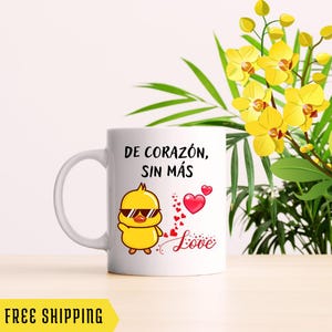 Puede incluir: Taza de cerámica blanca con un pollito amarillo de dibujos animados con gafas de sol y el texto "DE CORAZÓN, SIN MÁS Love" en rojo y negro.