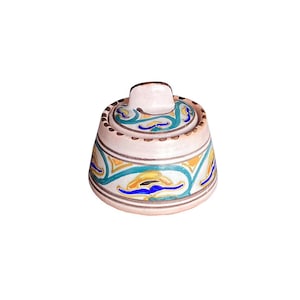 May include: A ceramic sugar bowl with a lid featuring a hand-painted pattern of teal, yellow, and blue abstract shapes on a cream-colored base. The bowl has a rounded shape with a small knob on the lid and brown painted trim along the edges.