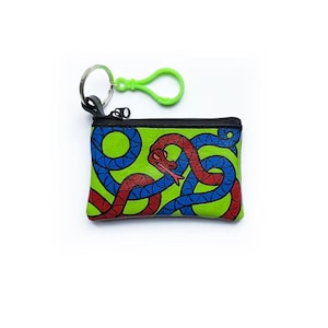 May include: A rectangular coin purse featuring a vibrant green background with a graphic illustration of intertwined red and blue snakes. The pouch has a black zip closure along the top edge and includes a silver metal keyring with a bright lime green plastic clip attached to the side.