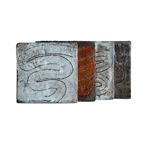 May include: A set of four square ceramic tiles with a textured, uneven surface. Each tile features a hand-carved, continuous swirling line pattern. The colours include a white, a deep reddish-brown, a light grey, and a dark charcoal black finish.